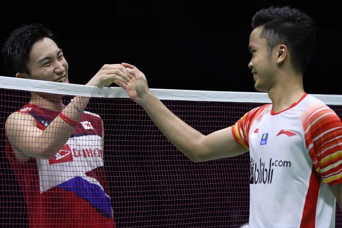 Anthony Sinisuka Ginting (kanan) bersalaman dengan Kento Momota usai bertanding.